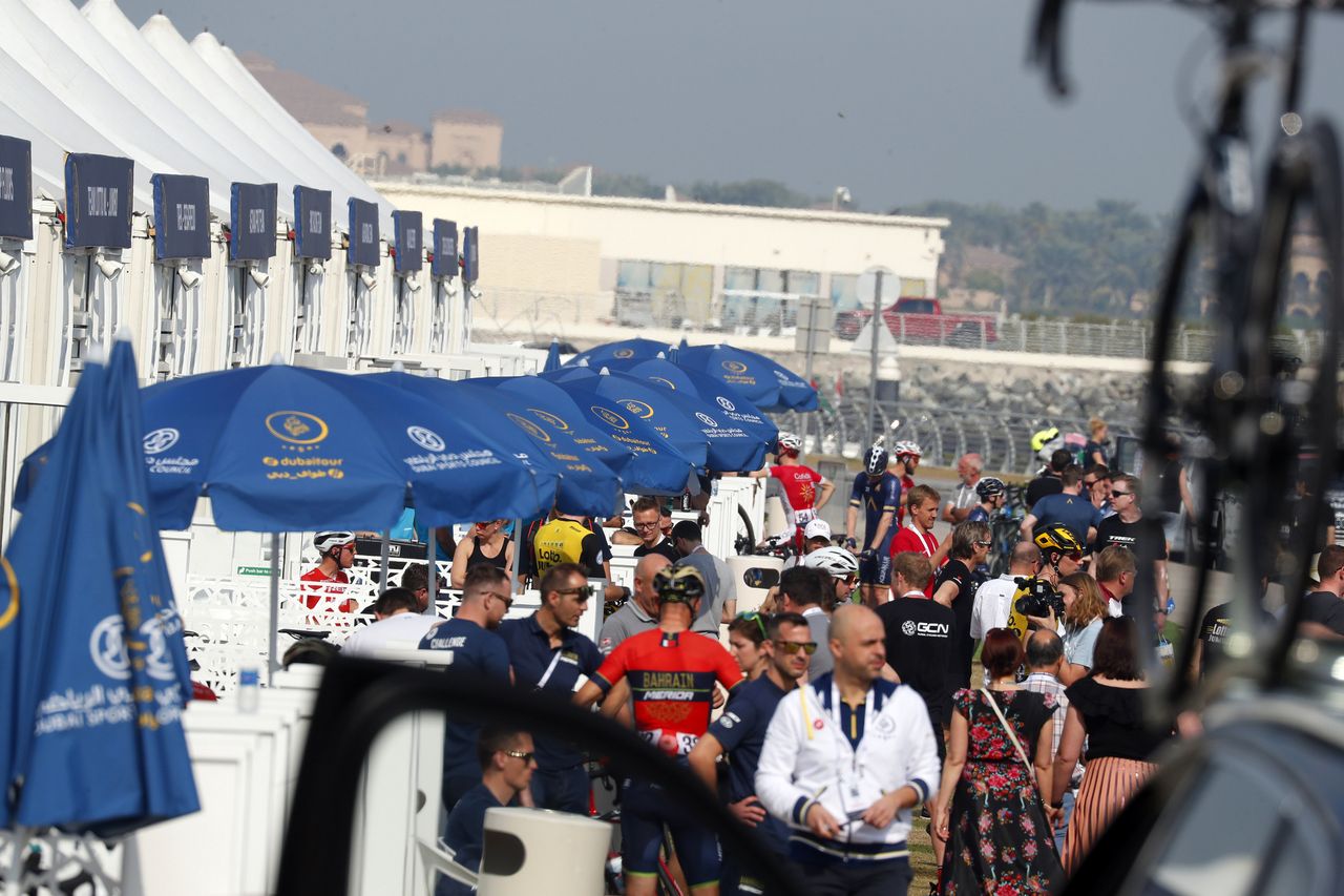 Riders, staff and journalists mill around the paddock ahead of stage 2