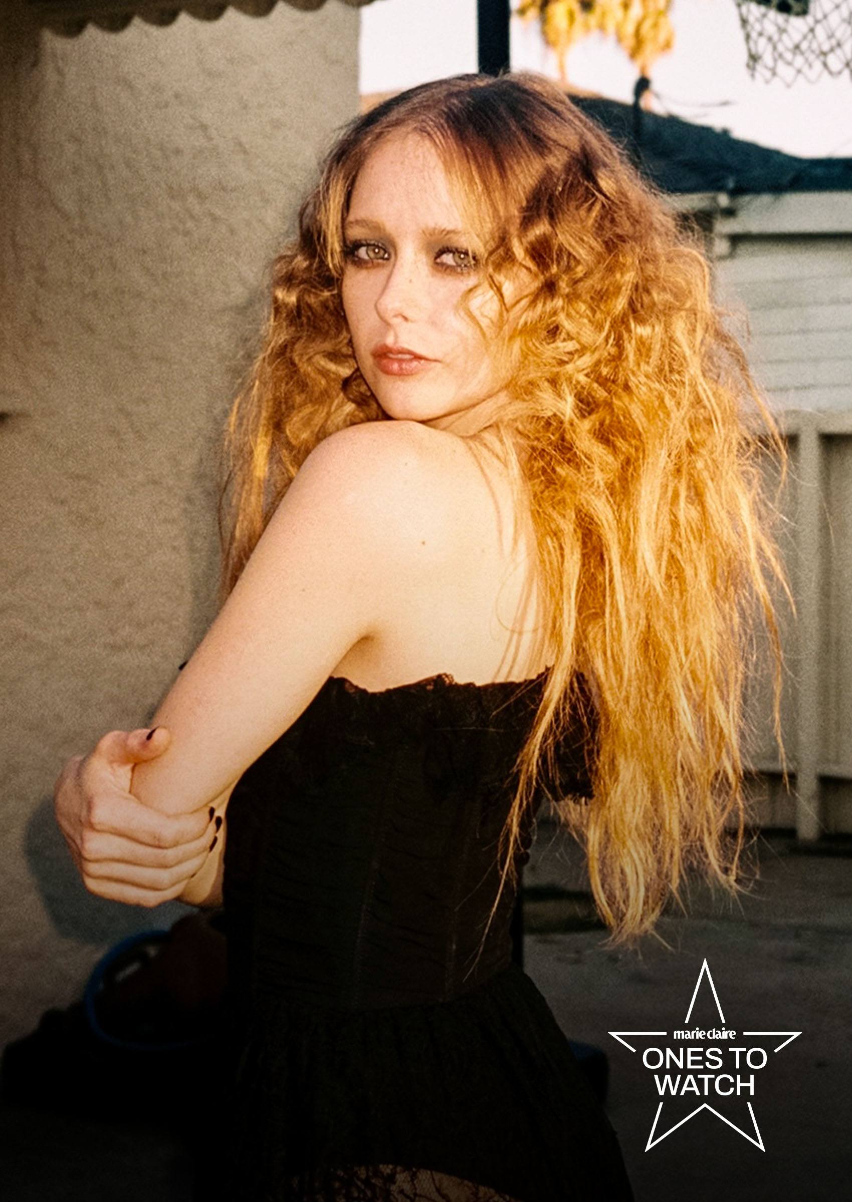actress and singer suzanna son poses next to a wall with her hair teased and wearing a black gown