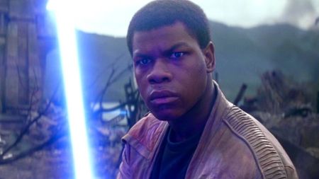 John Boyega as Finn wielding Luke Skywalker's lightsaber in Star Wars: The Force Awakens