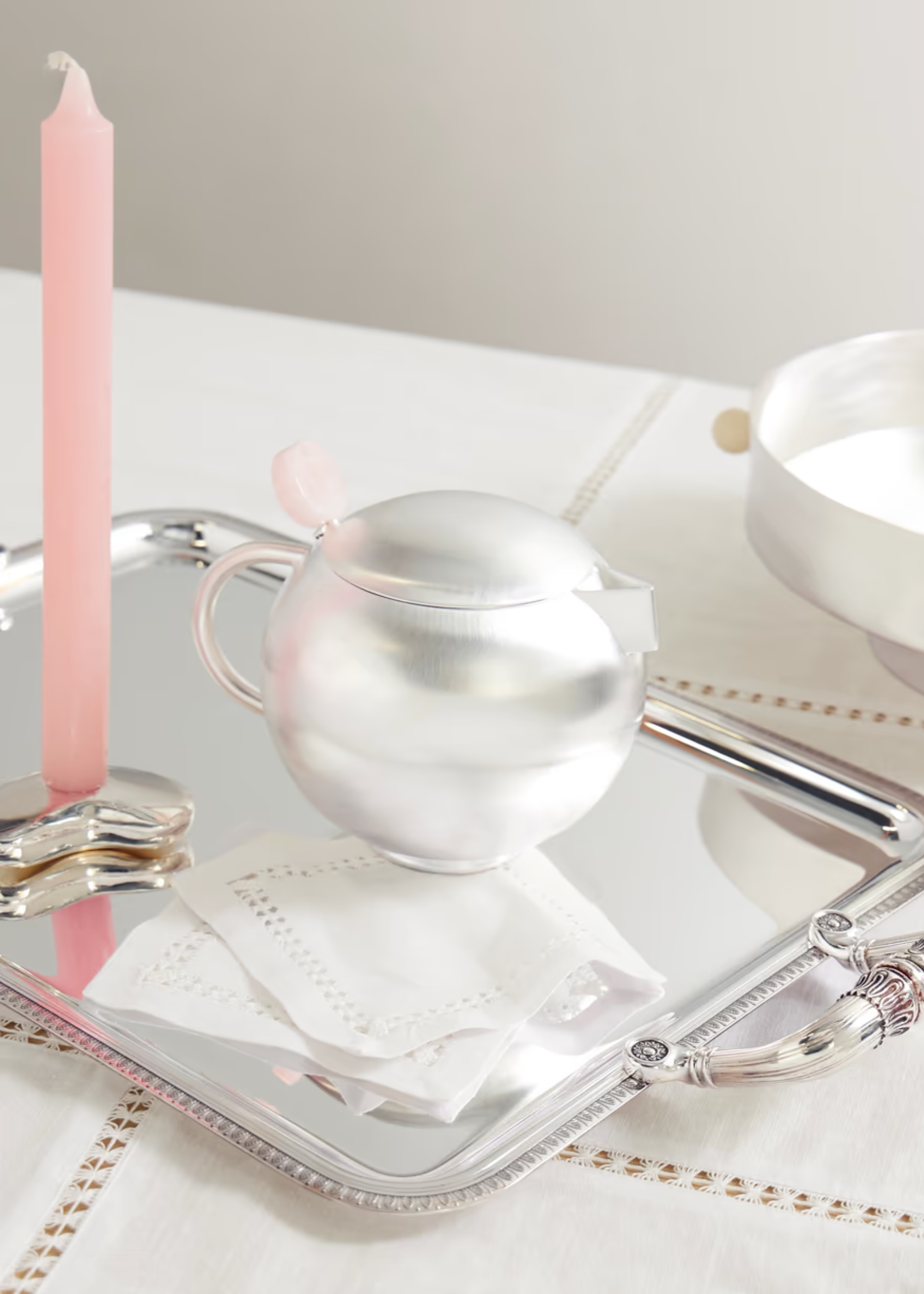 A brushed silver and rose quartz teapot on a serving tray