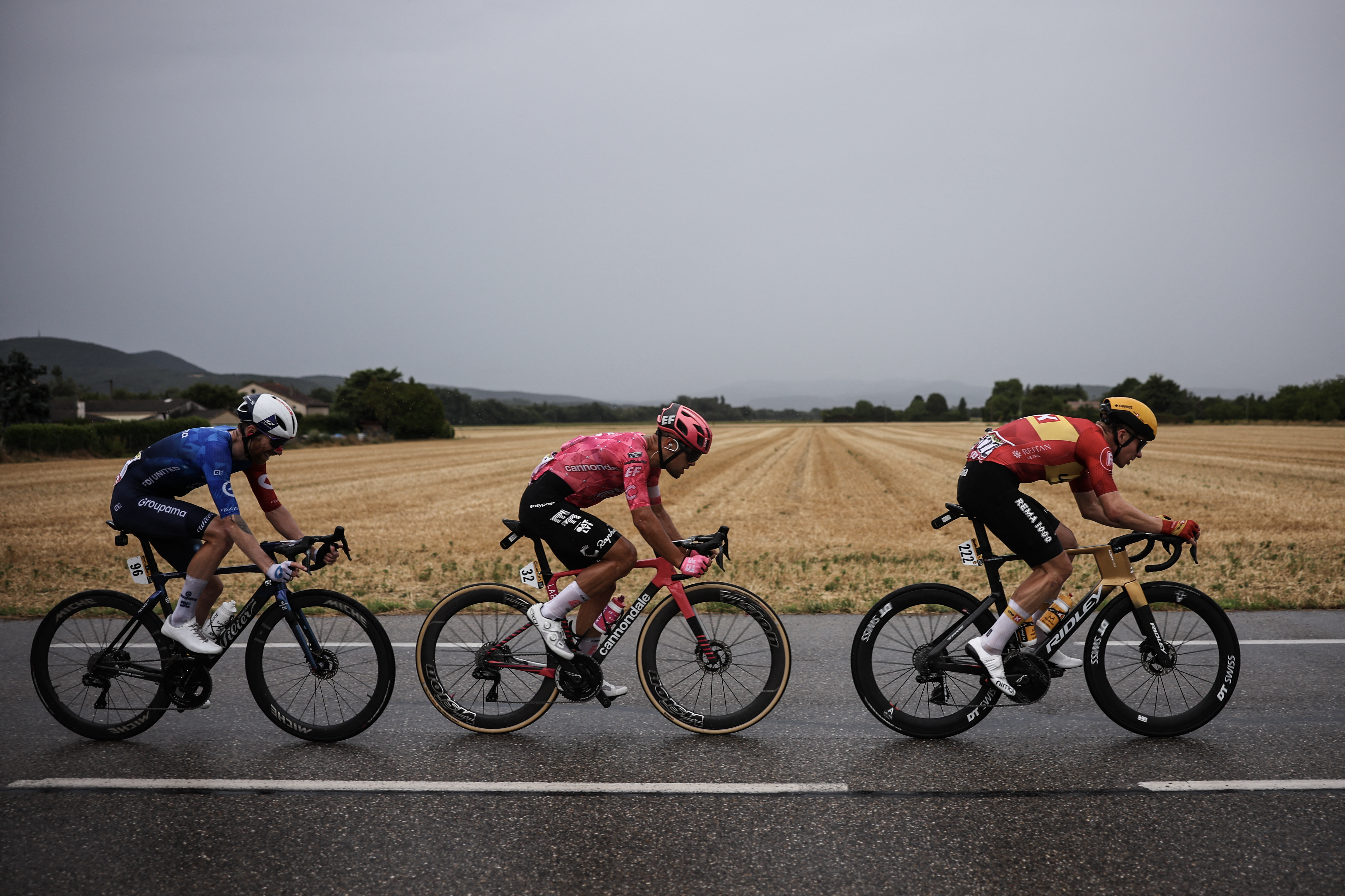 Groupama - FDJ team's French rider Quentin Pacher (L), EF Education - EasyPost team's Italian rider Vincenzo Albanese (C) and Uno-X Mobility team's Norwegian rider Jonas Abrahamsen (R) cycle in a breakaway in the rain during the 17th stage of the 112th edition of the Tour de France cycling race, 160.4 km between Bollene and Valence, southern France, on July 23, 2025. (Photo by Anne-Christine POUJOULAT / AFP) (Photo by ANNE-CHRISTINE POUJOULAT/AFP via Getty Images)