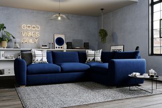 blue apartment style living room with blue couch, low shelving round the edge, record player, neon sign, black and white cushions, side table, rug