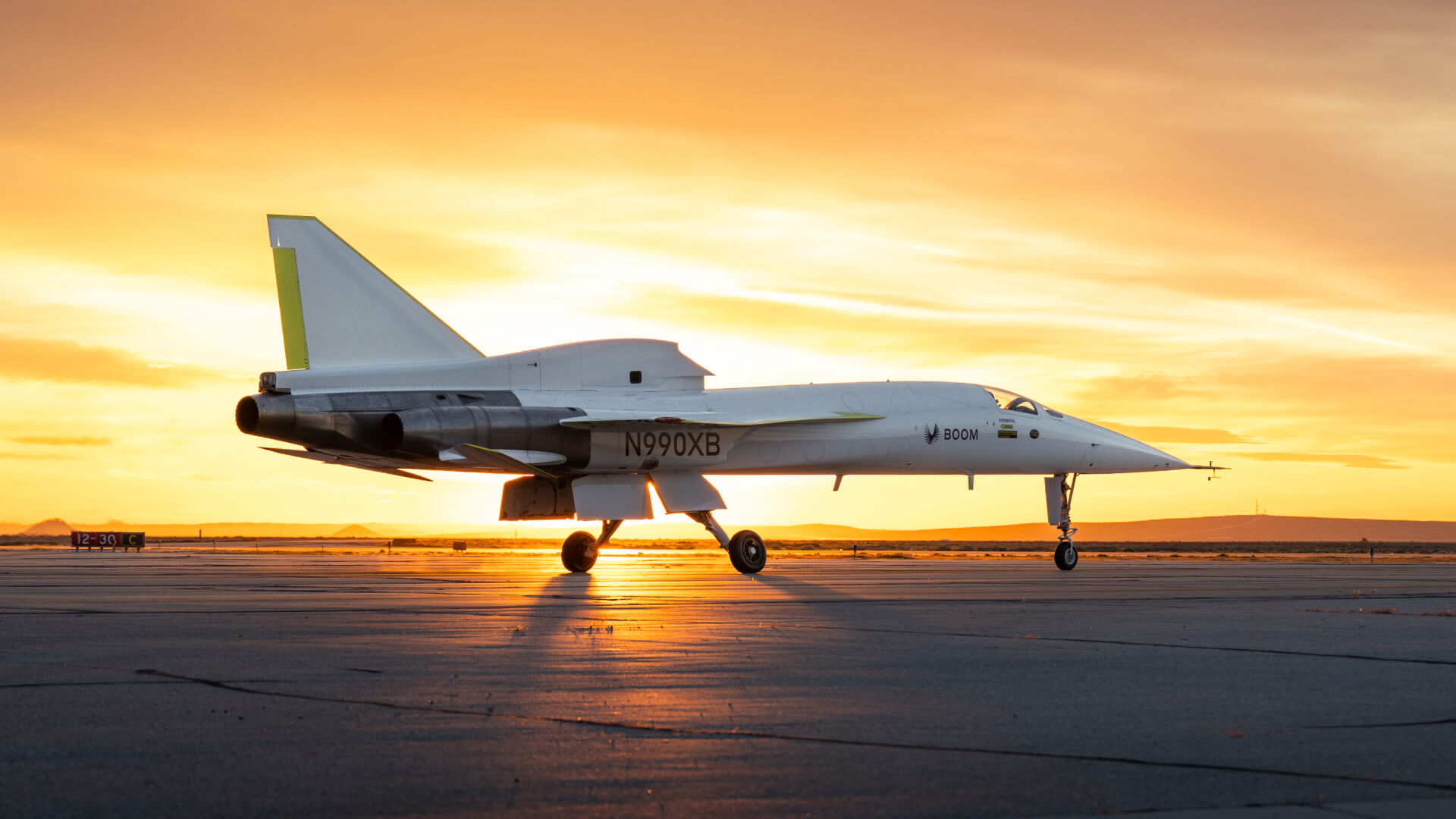 A white jet aircraft parked in front of a setting sun