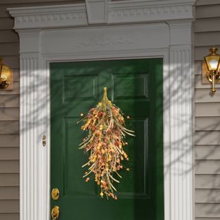 Green door with fall teardrop hung to it