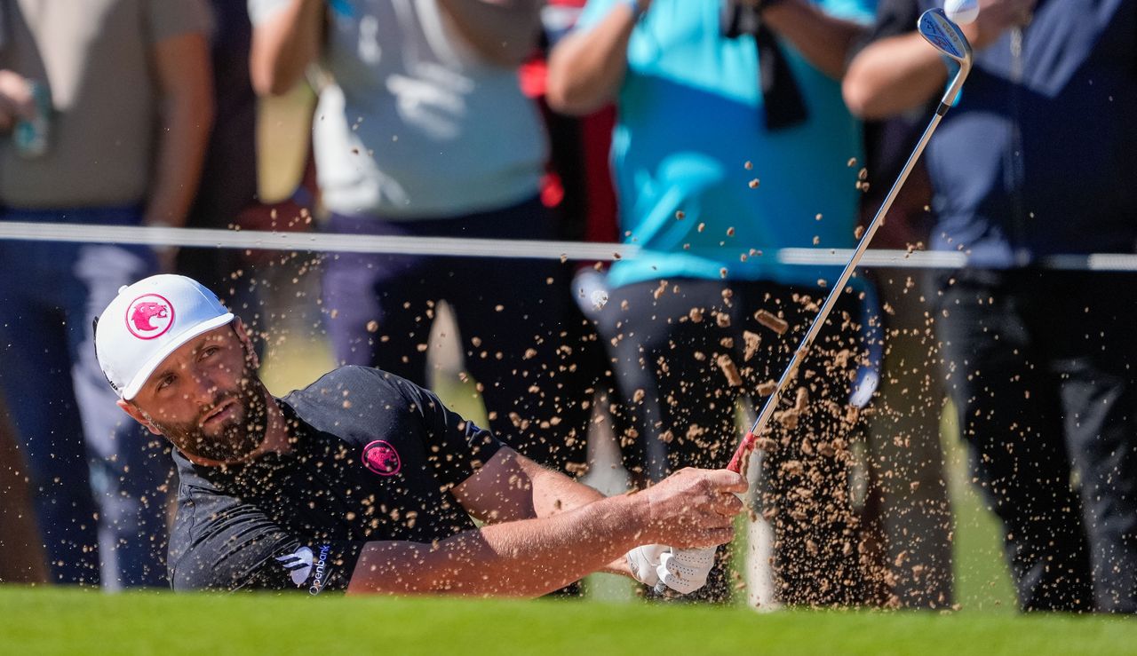 Jon Rahm strikes a shot from the bunker