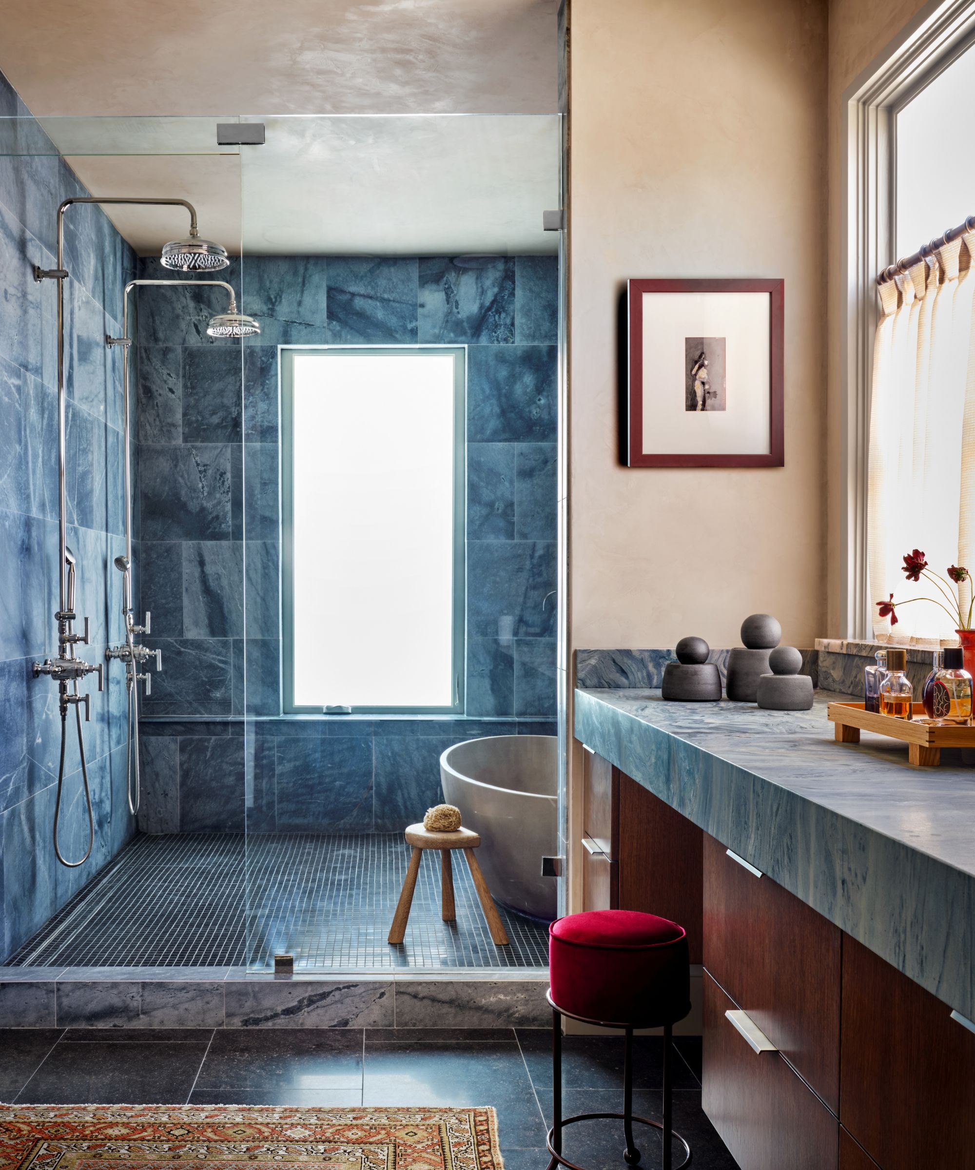 Bahtroom with blue marble tiles, walk-in shower, marble countertops, red stool and plaster walls