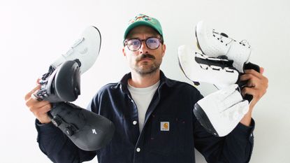 A white man holding a selection of cycling shoes for wide feet