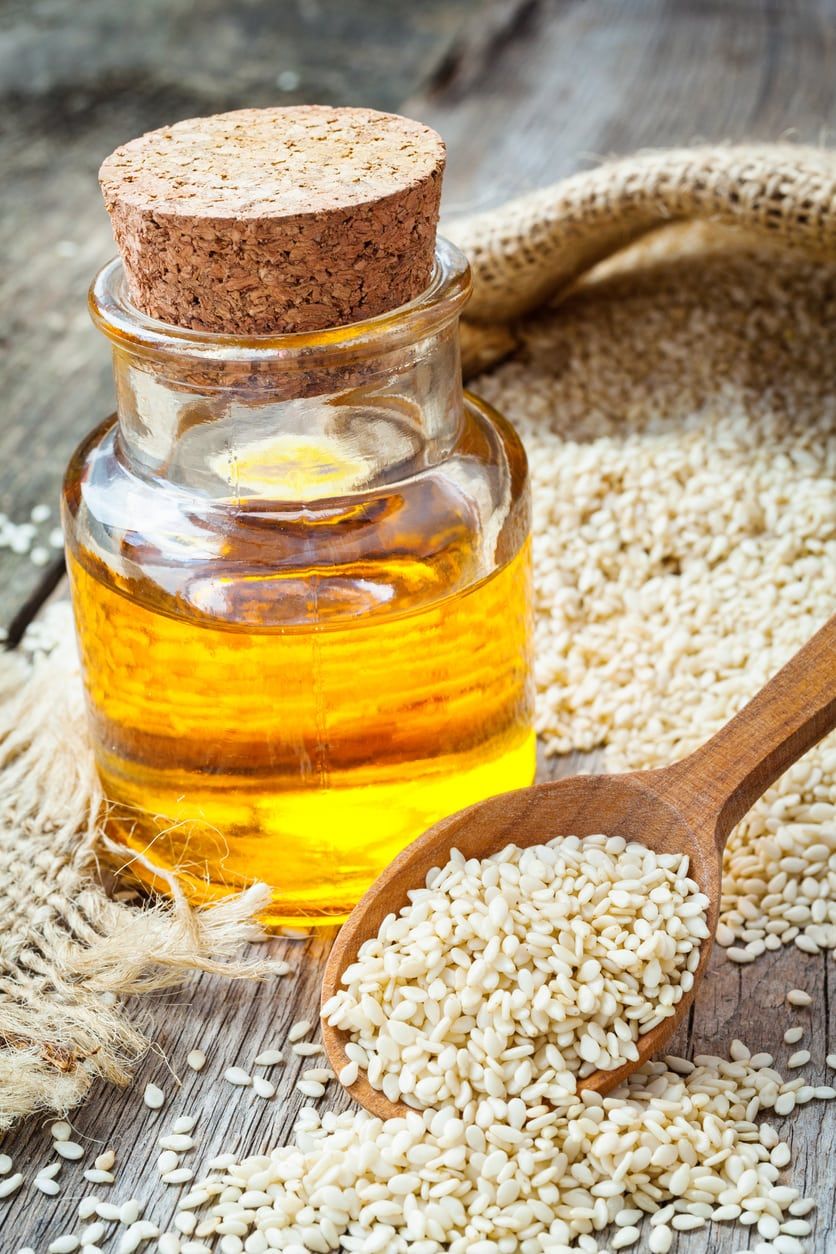 Sesame Seeds Surrounding A Glass Jar Of Sesame Oil