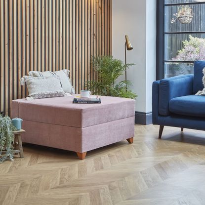 Darlings of Chelsea pink bed-in-a-box in a living room with a wooden parquet floor