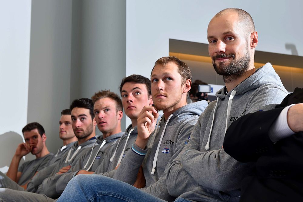 The team is lined up in the front row of the press conference.