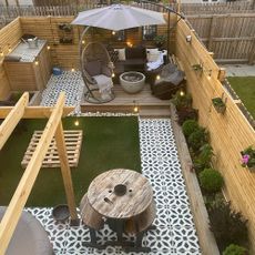 garden decking area with wooden wall fence sofa seating with cushion plants and light