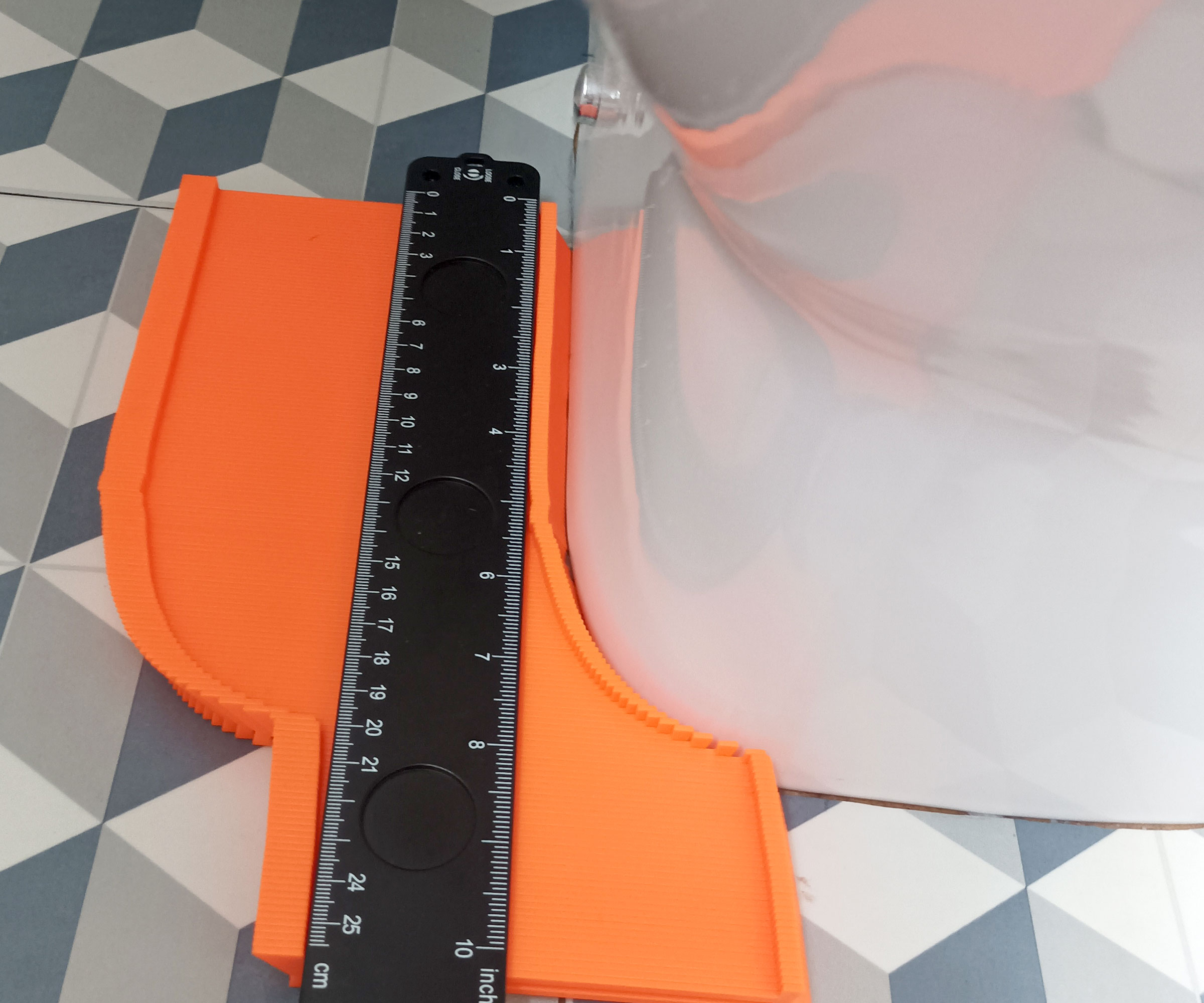 Orange and black contour gauge marking out curve of the base of the toilet lenghtways