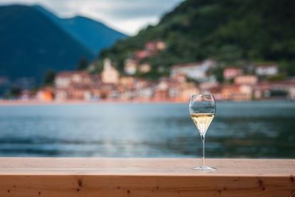 glass of sparkling wine by lake como