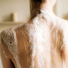 Best body wash for eczema - the back of a woman covered in shower gel lather - gettyimages 1447508636