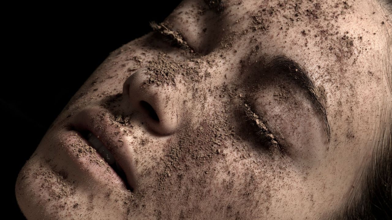 Close up of a womans face wearing a powdered mud mask