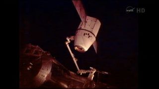 The Dragon capsule is shown here on space station cameras, attached to the station's robotic arm after it is disconnected from the orbiting laboratory to end its five-day stay.