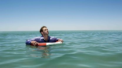 Businessman floats with a life preserver around him.