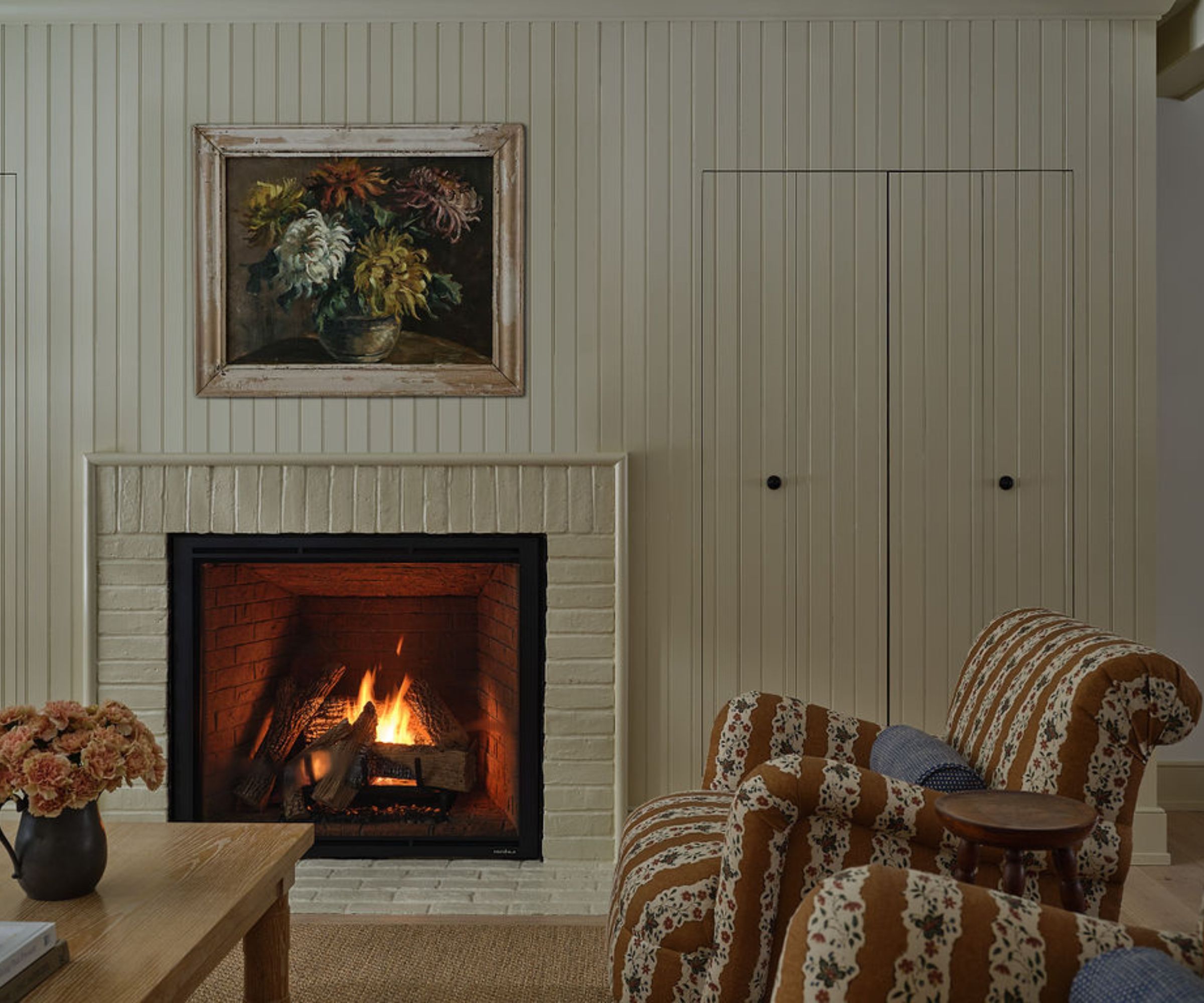 A cozy living room with white wall paneling and two patterned armchairs