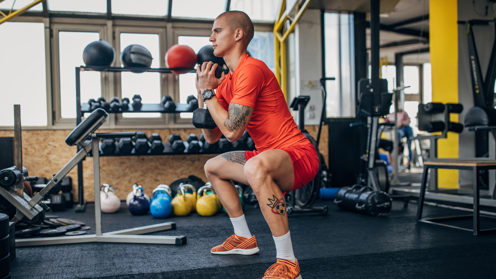 A man in a home gym doing a dumbbell goblet squat
