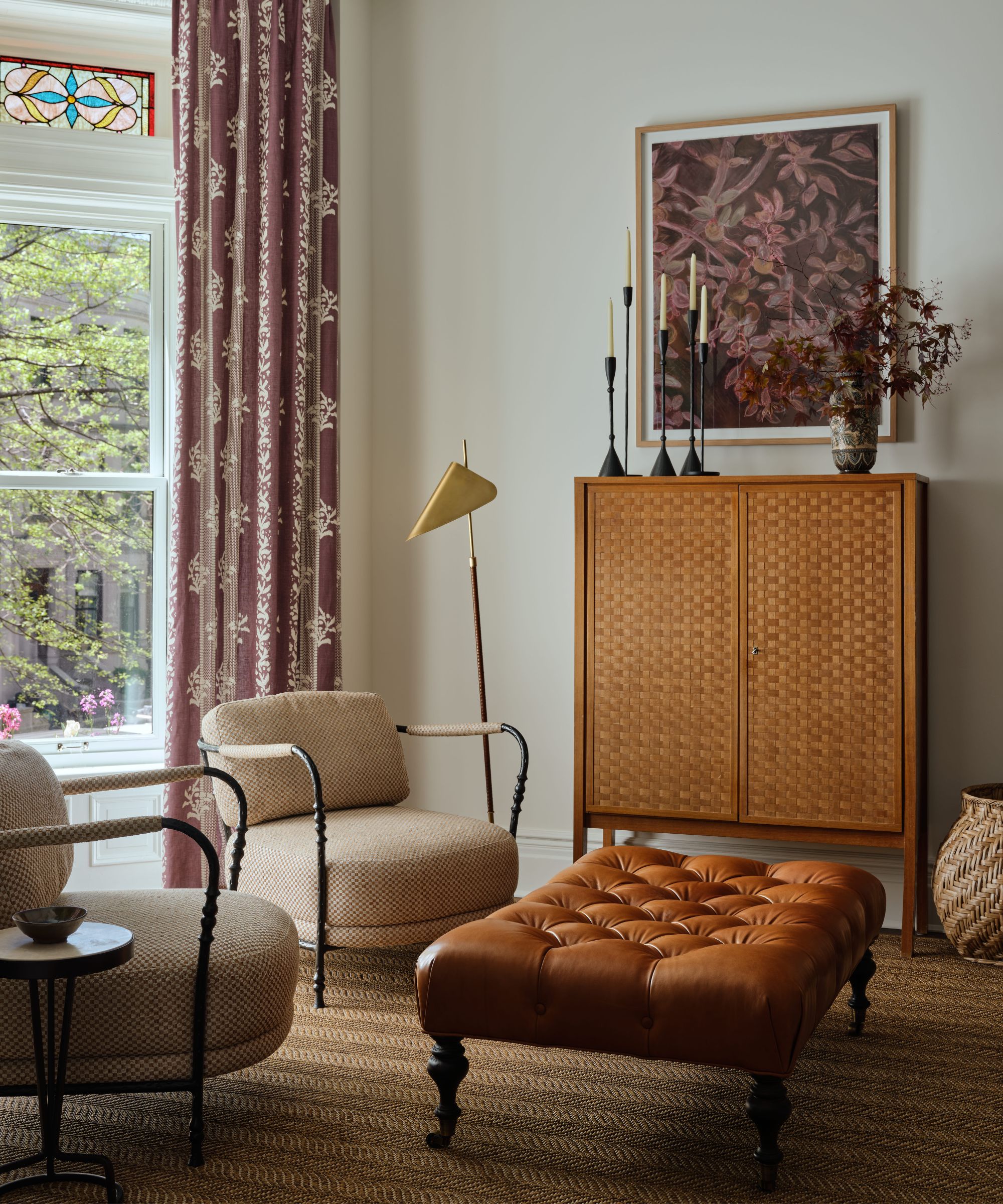 a layered vintage style living room with mauve printed curtains over a window with stained glass