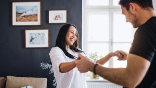 Woman and man dancing in bedroom together, having fun after solving big relationship issues
