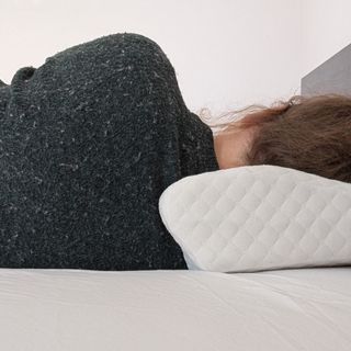 A woman in a green jumper with her head on a pillow