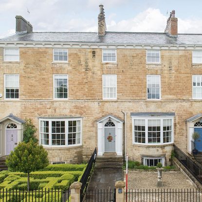 brick wall mansion with white window grey door roof top and lawn
