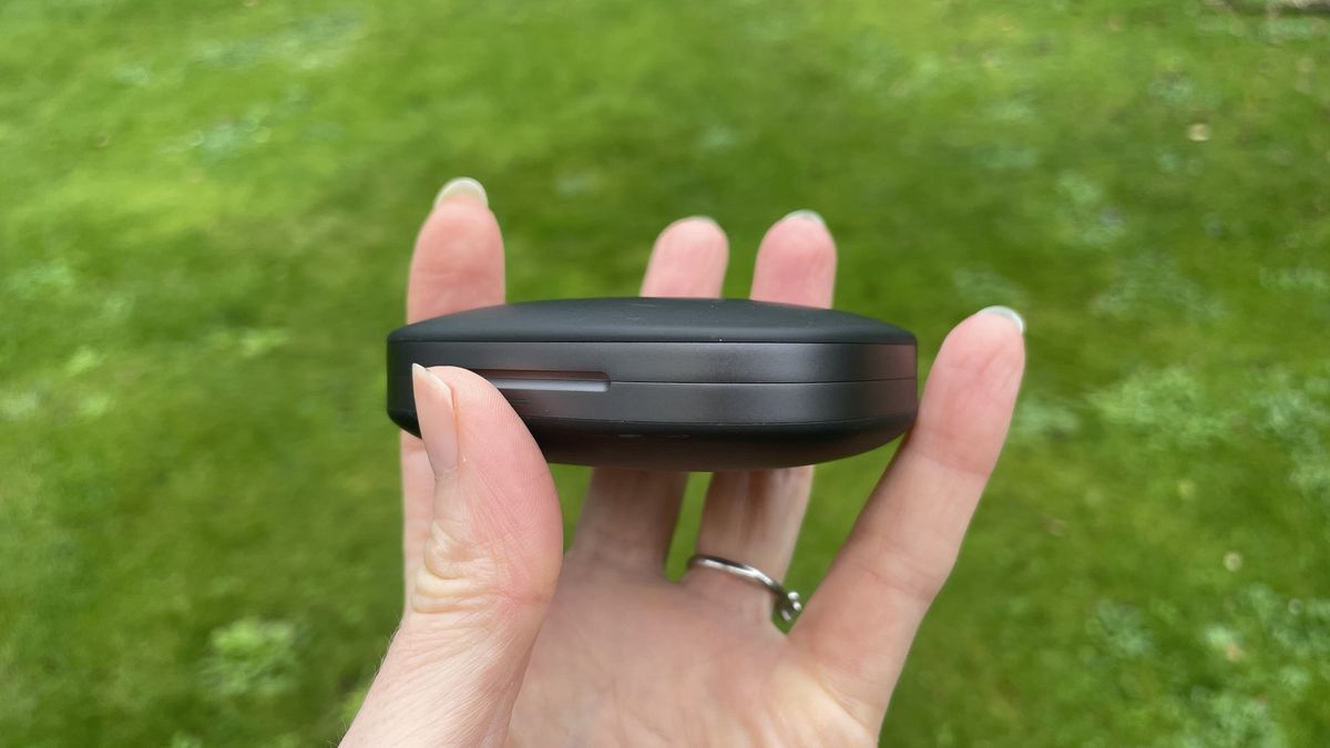 Shokz Openfit Pro outside, outside held in a woman's hand, with green grass in the background