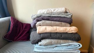 A selection of the best weighted blankets as tested by Hannah Holway on a grey sofa.
