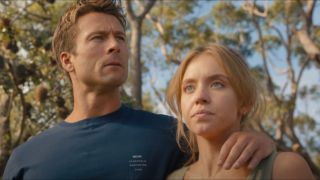 Glen Powell resting his arm around Sydney Sweeney's shoulder looking to his right, Sweeney is looking straight ahead.