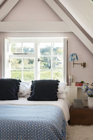 Bed by window, blue and white blanket