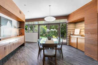 A dining area with floor to ceiling windows and built in wooden cabinetry