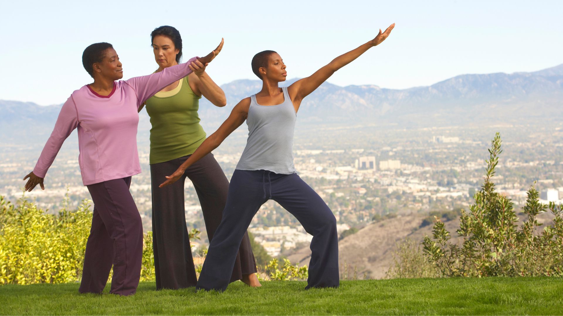 An instructor shows a mature woman how to practice Tai Chi on a hillside.