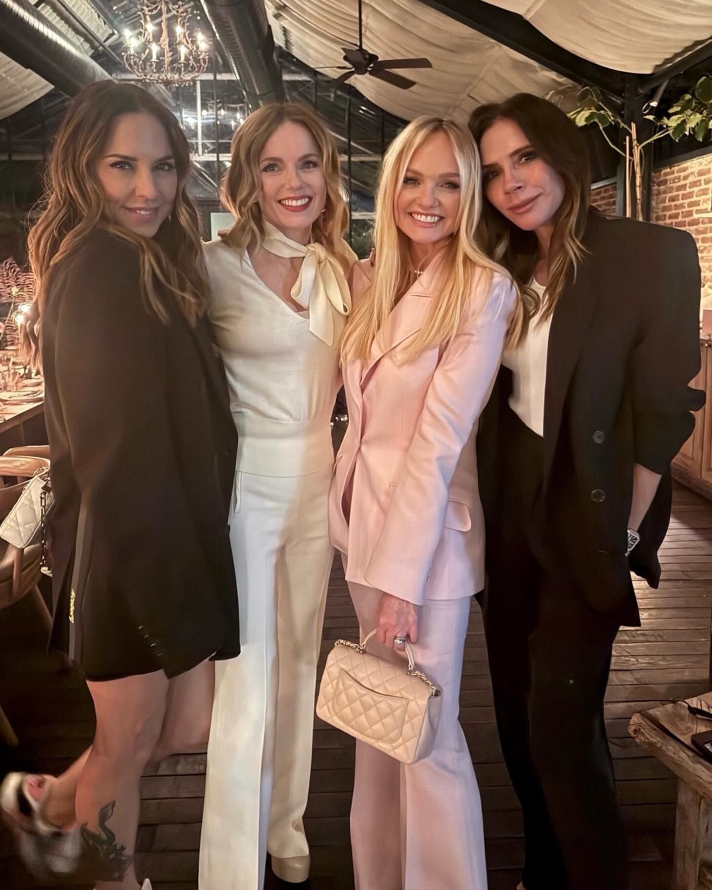 Victoria Beckham poses for a photo wearing an oversized suit with a white tank top.