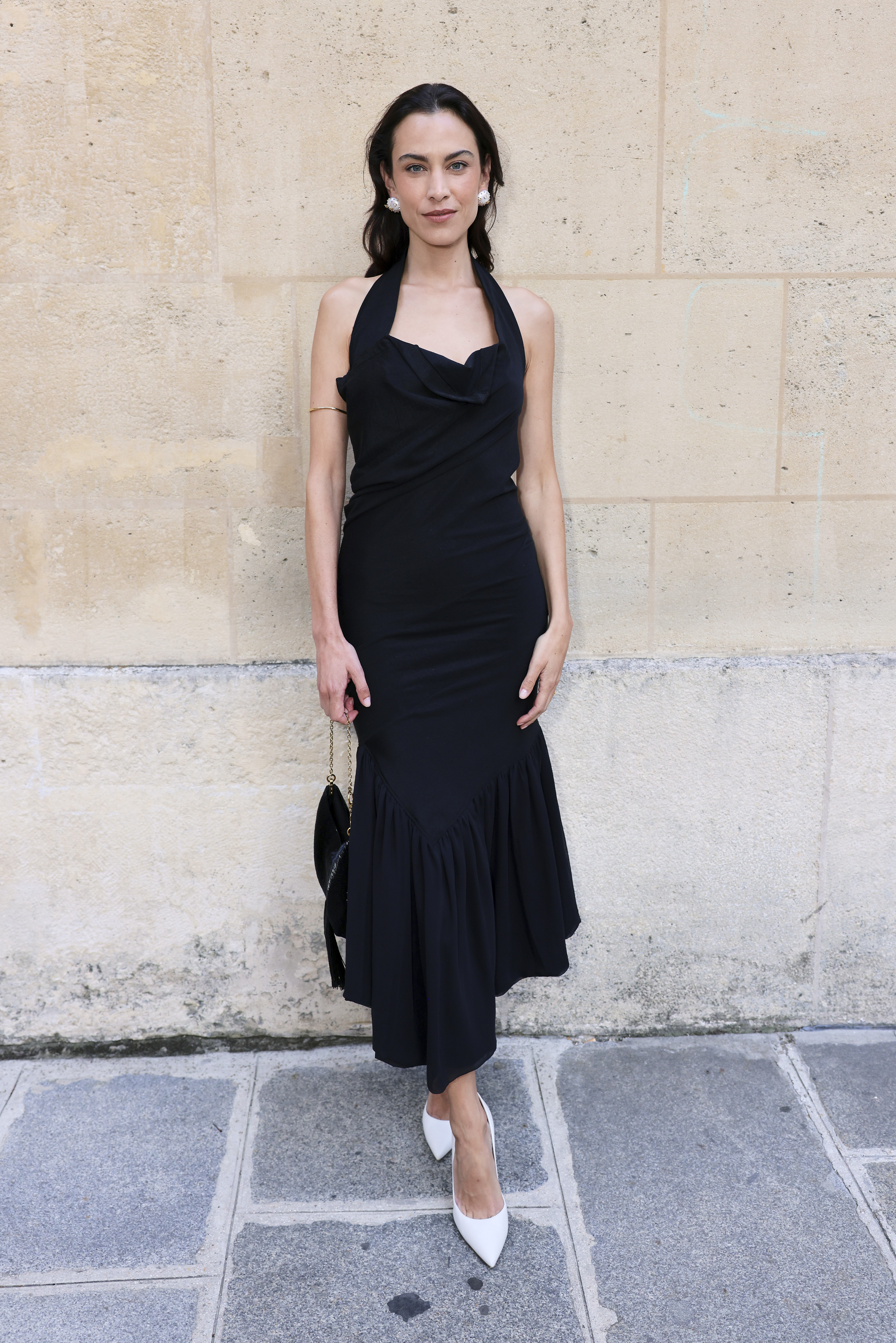 Alexa Chung wears a black halterneck dress with white heels and a black bag in Paris.