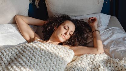 Woman lying in bed asleep, sleep & wellness tips