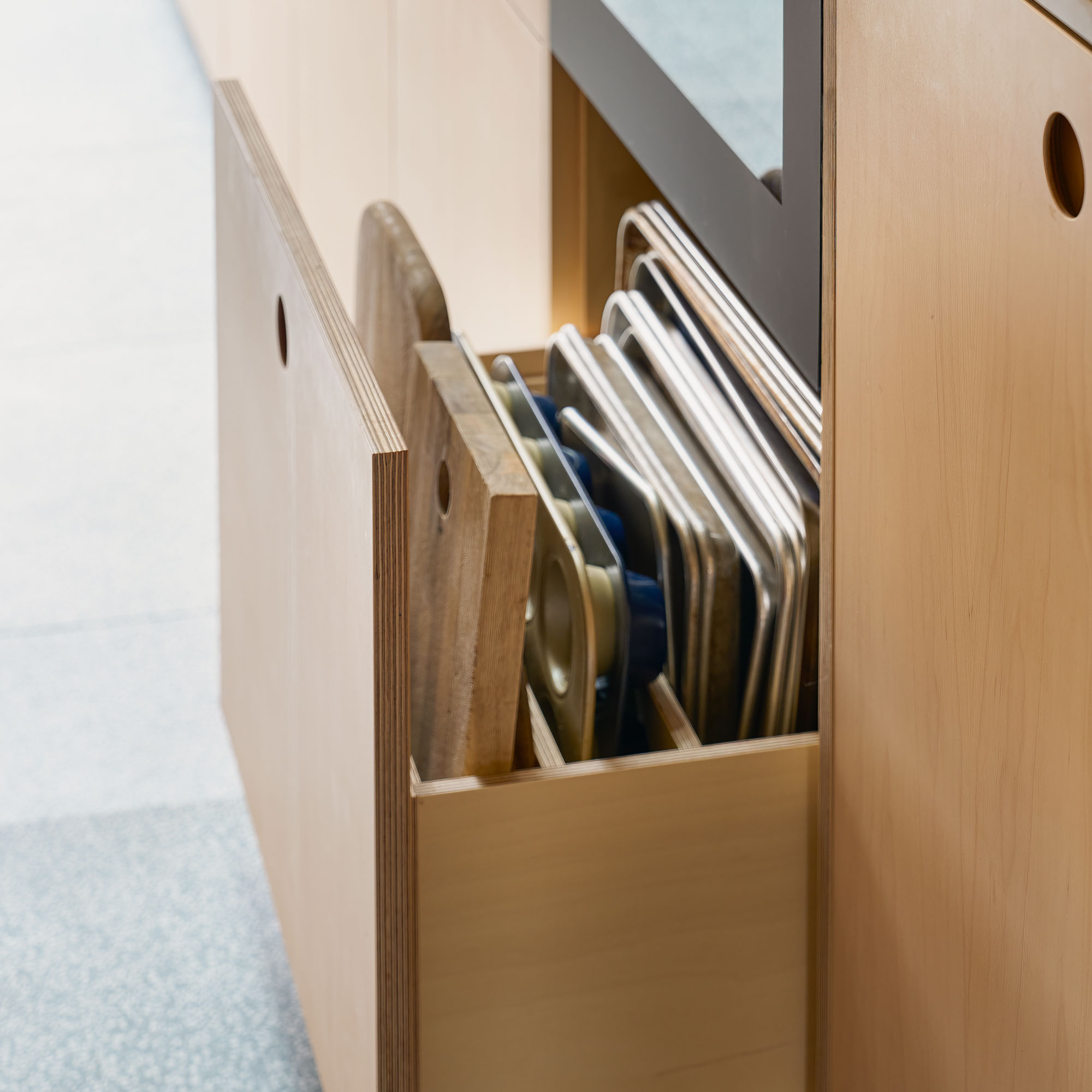 Plywood kitchen drawer with dividers holding baking trays and chopping boards.