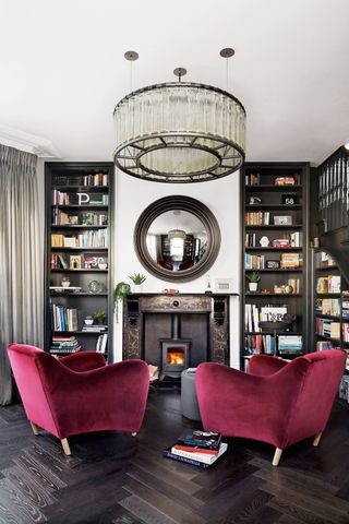 Dark living room with built in bookcases and plum colored accent chairs