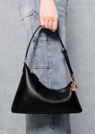 a model holds an Aupen leather bag in front of her jeans