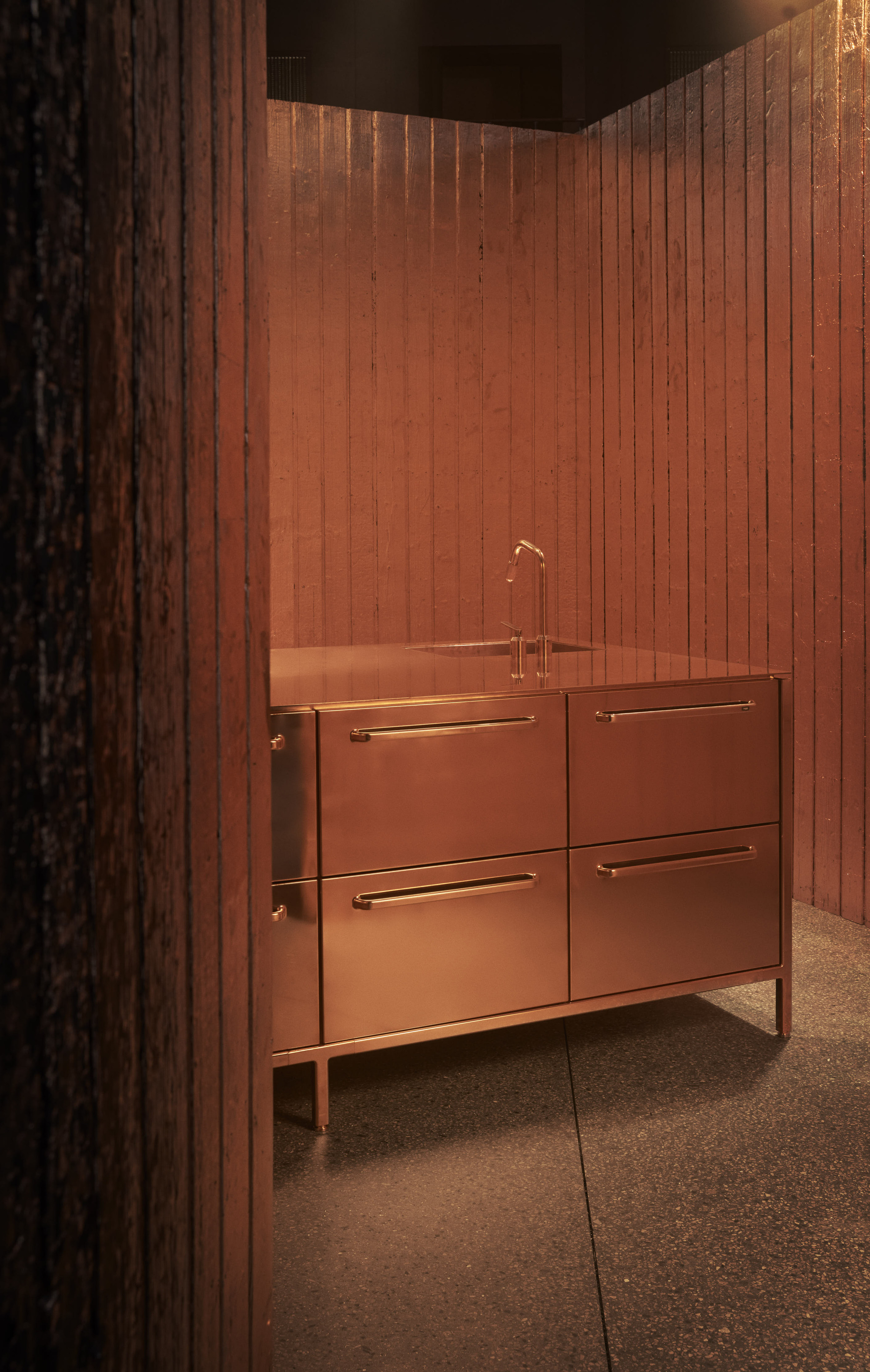 copper kitchen from Vipp with copper leaf walls, stone floors, freestanding kitchen unit