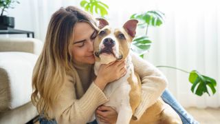 woman cuddling her pitbull terrier