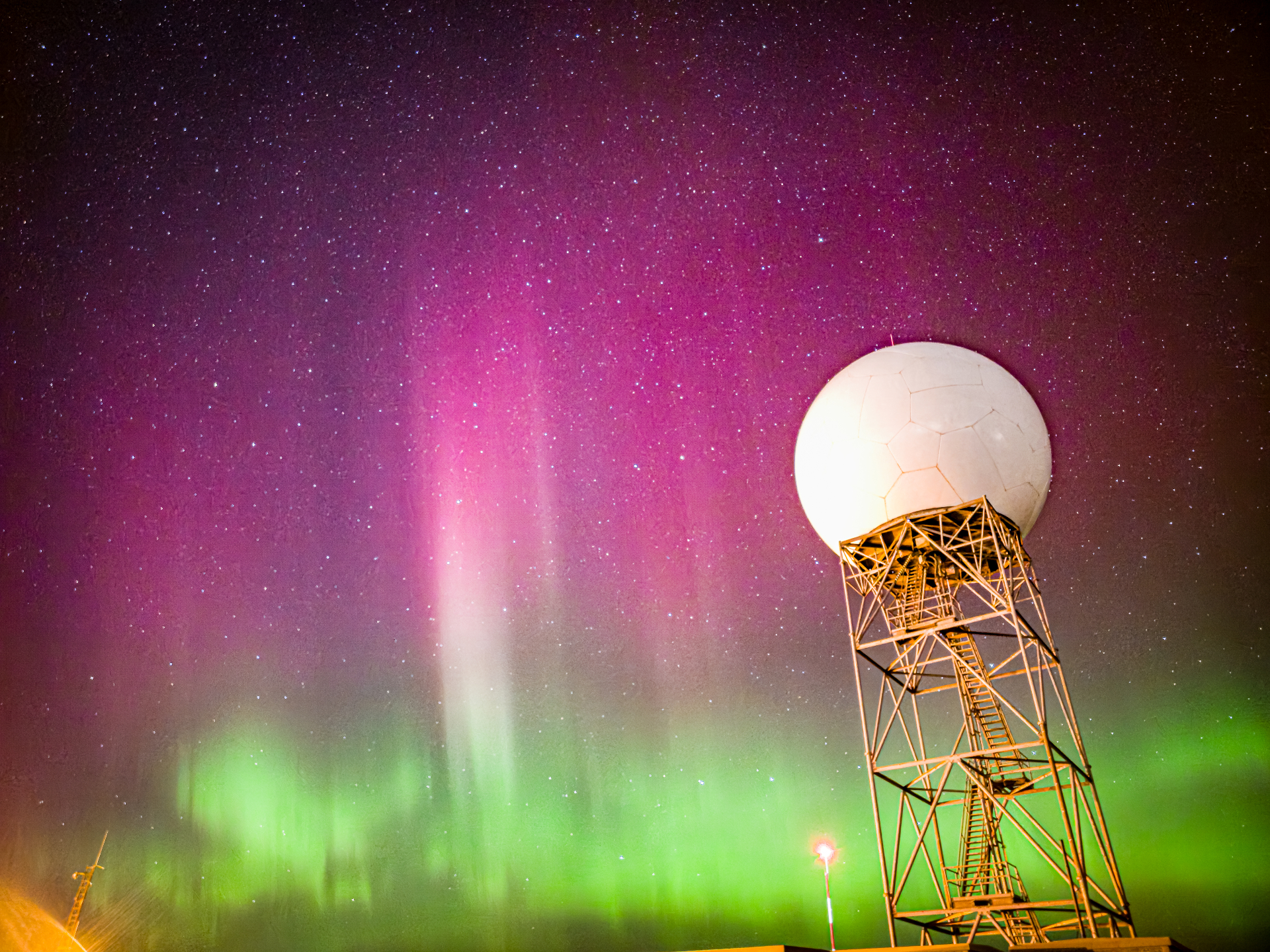 يتراقص الشفق القطبي الوردي والأرجواني النابض بالحياة فوق الشفق الأخضر.