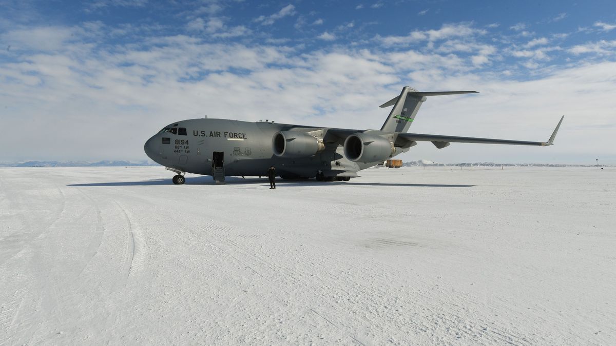 a large grey airplane sits on a snow-covered plateau