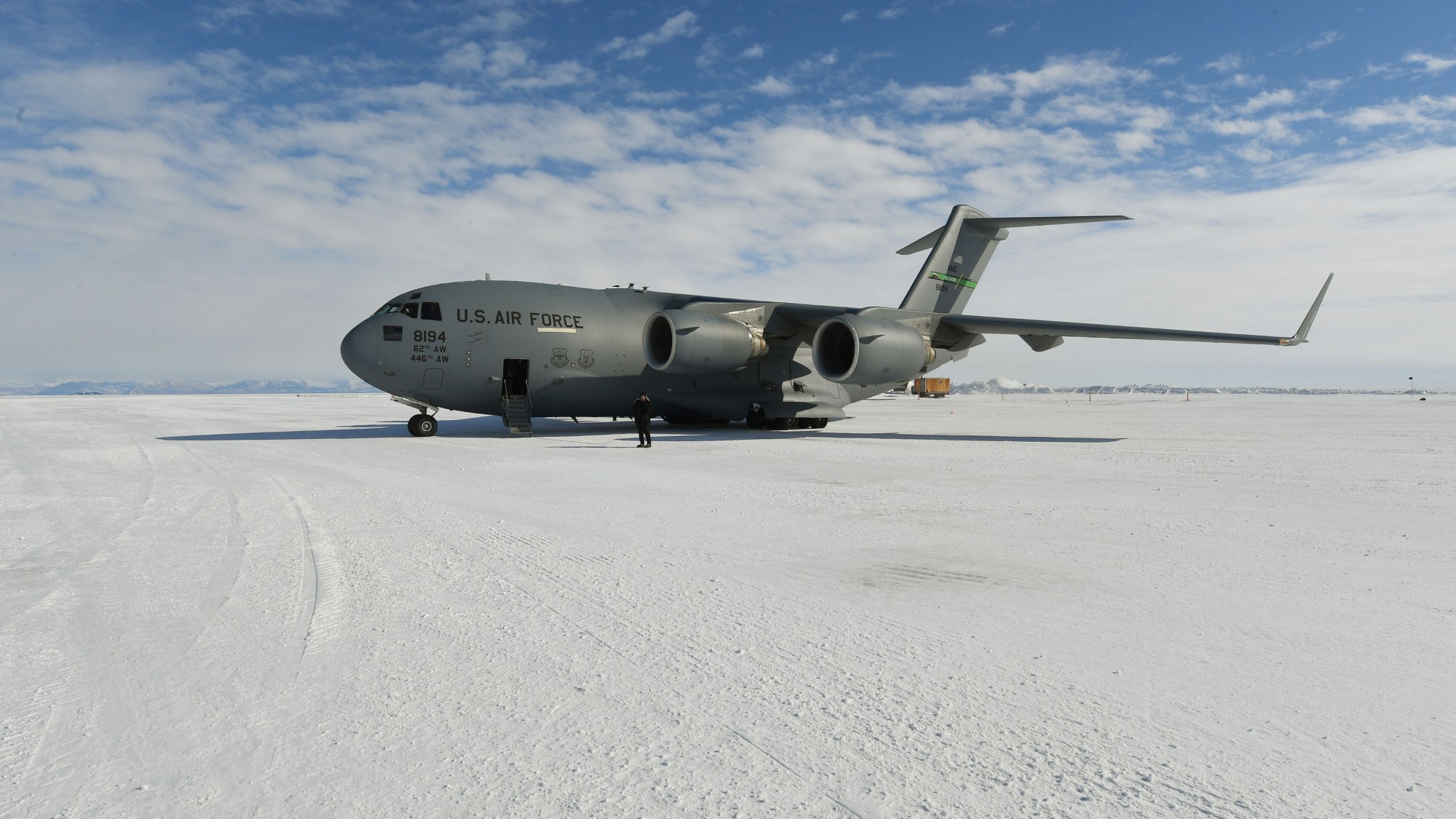 a large grey airplane sits on a snow-covered plateau