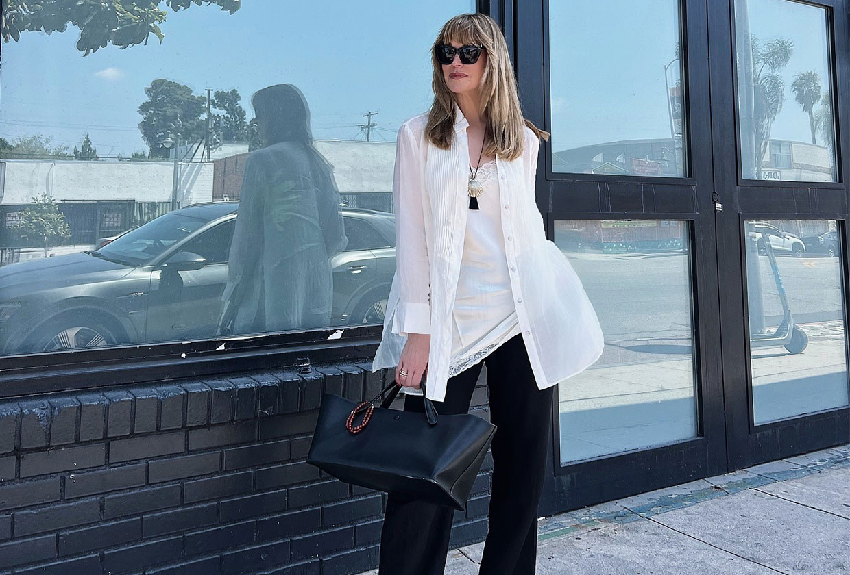 Jen Andrews Cater wearing an open white button-down over a white tank and black trousers.