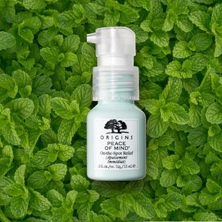 A bottle of Origins Peace of Mind On-The-Spot Relief in front of a green background