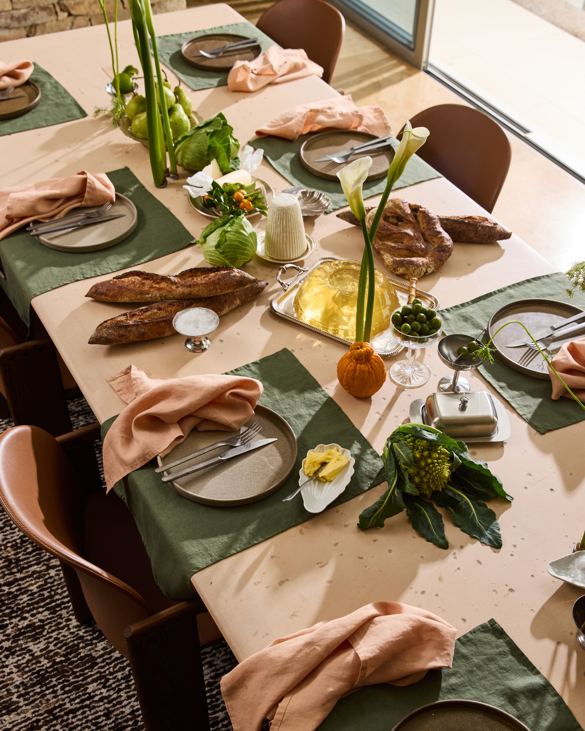 a pink table with green placemats, pink napkins, lily flowers and food on display