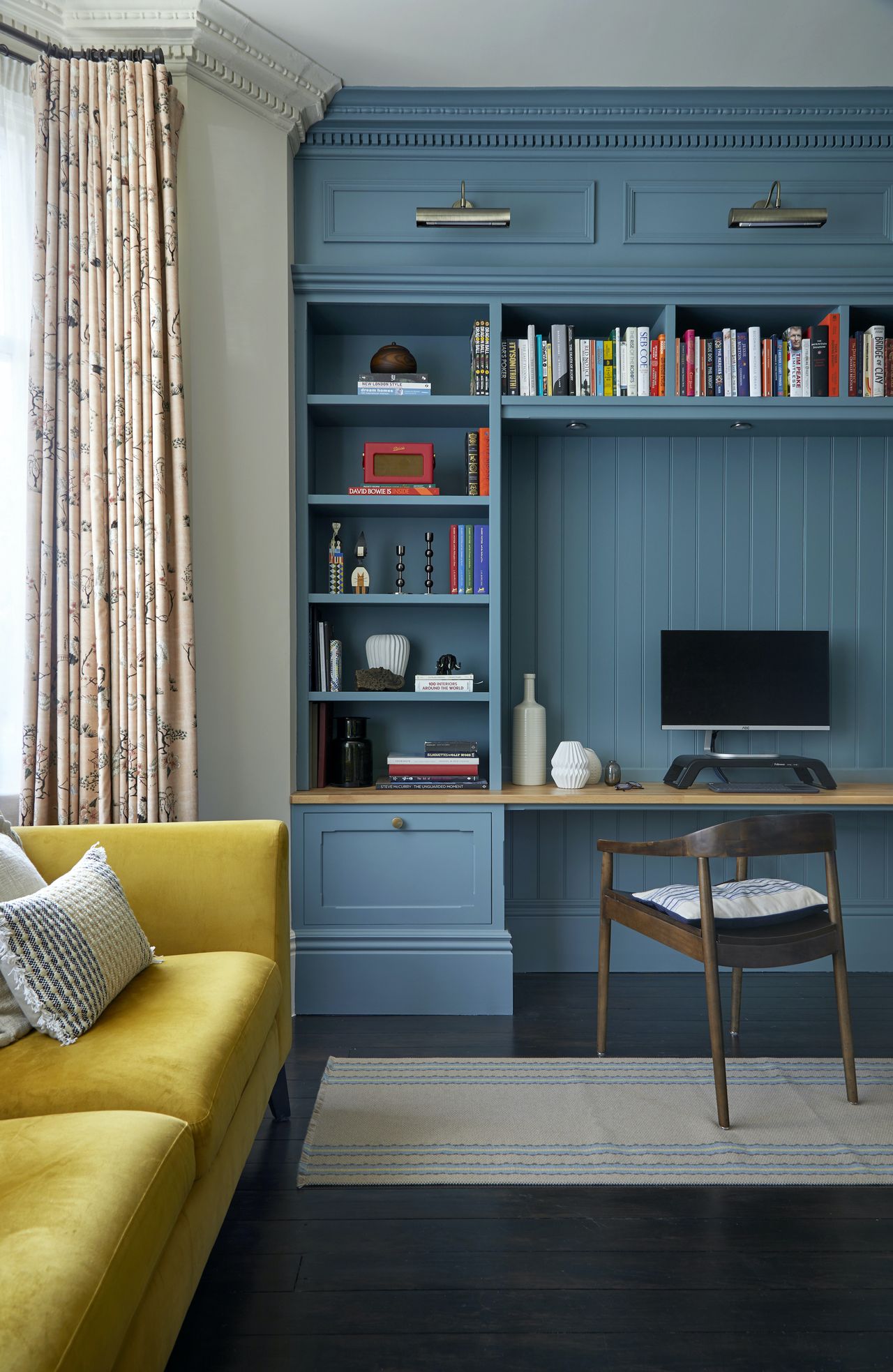 Blue home office with computer monitor, chair and bookshelves