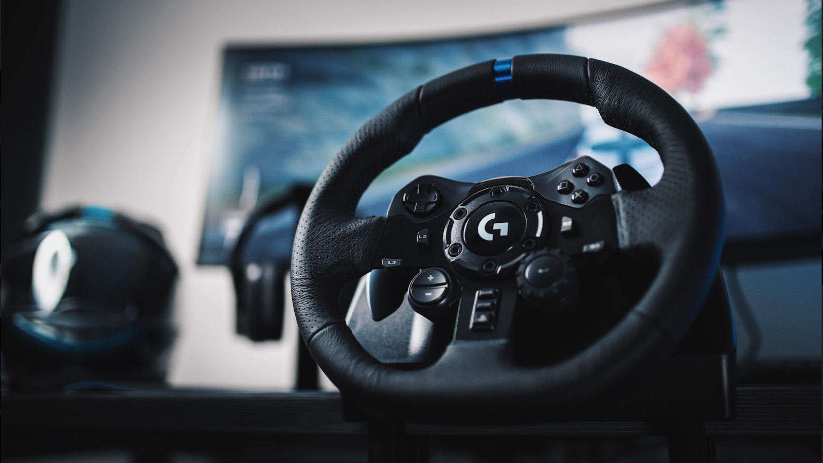 The Logitech G923 racing wheel with a curved monitor in the background.