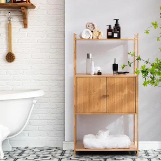 a wooden freestanding bathroom cabinet next to a white tub with white and black tiles and white walls